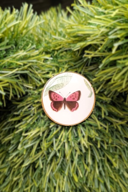 Broche artisanale en porcelaine ancienne avec motif papillon et feuillage botanique.