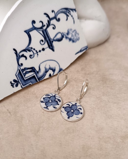 Gros plan sur les boucles MOUSTIERS en faïence ancienne, révélant la finesse du décor et le travail artisanal de transformation.