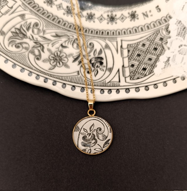 Collier artisanal en faïence ancienne, motif noir et blanc, pendentif plaqué or 24 carats et chaîne en acier inoxydable.