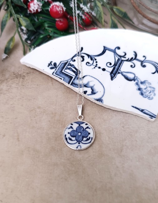 Collier en faïence ancienne posé en décor. Pendentif 18 mm en plaqué argent, création artisanale française issue d’une assiette de Moustiers sauvée et revalorisée.