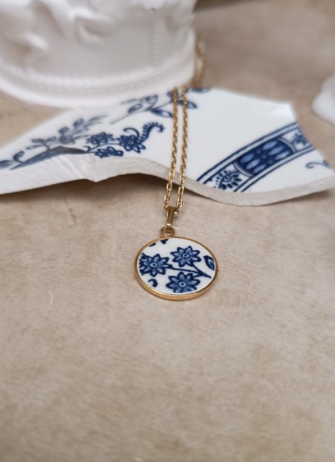 collier-bleu-vintage-porcelaine-leger-delicat-chaine-acier-inoxydable Découvrez le collier Bleu Vintage, pièce unique en porcelaine anglaise ancienne, posé pour mettre en valeur son motif fleuri bleu sur fond blanc.