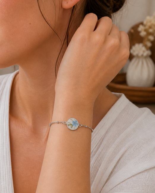Bracelet Myosotis porté, bijou en assiette recyclée aux fleurs bleues.