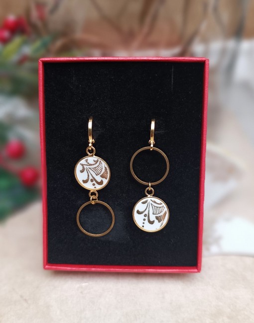 Boucles d’oreilles Orion dans un écrin prêt à offrir, accompagnées de la carte d’identité du modèle et du parchemin expliquant la démarche artisanale.