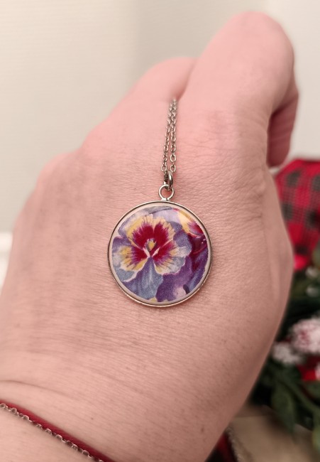 Gros plan sur le motif et la texture du pendentif en faïence ancienne, pièce unique plaquée argent.