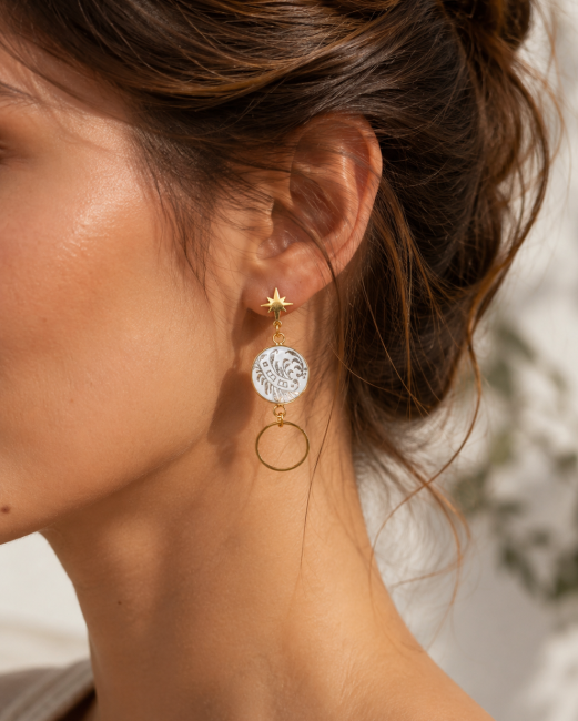 boucles-celestes-holographiques-portees.jpg Boucles Célestes asymétriques portées, grand modèle aux reflets dorés holographiques qui changent avec la lumière.