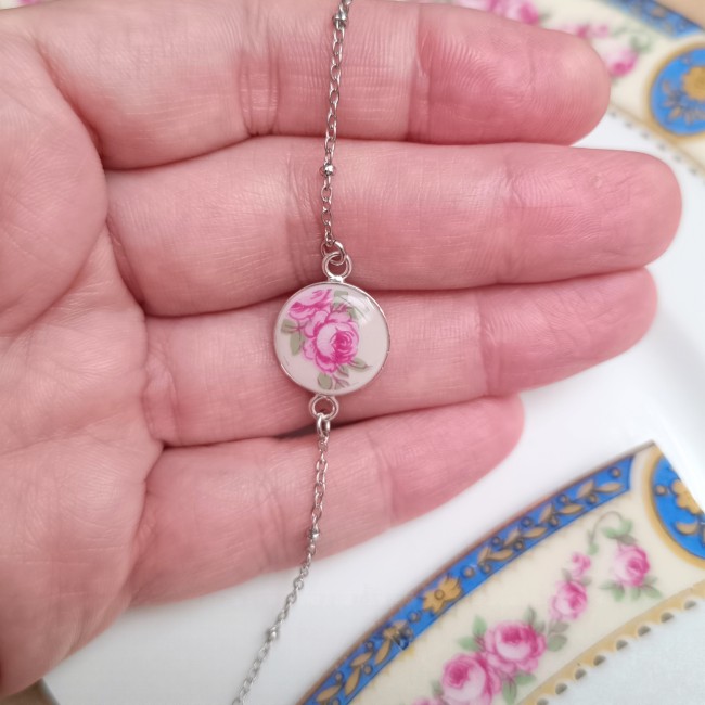 Bracelet en porcelaine de Limoges présenté en main pour visualiser son petit médaillon floral de 14 mm.