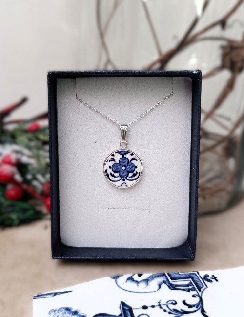 Photo du collier en faïence de Moustiers présenté dans son écrin. Pendentif rond 18 mm en plaqué argent 0,3 micron, création artisanale française à partir d’une assiette ancienne upcyclée.