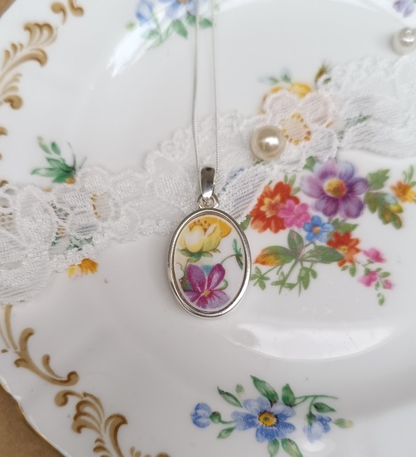 Pendentif Poésie présenté en gros plan pour apprécier la finesse du décor floral en porcelaine anglaise et les détails des roses jaunes.