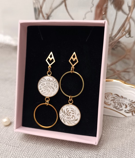Boucles Célestes en faïence ancienne présentées dans leur écrin, pièce unique artisanale prête à offrir.