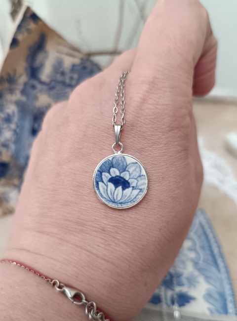Collier Bleu Vintage présenté en main pour apprécier les proportions du pendentif rond de 18 mm et la finesse du décor floral bleu.