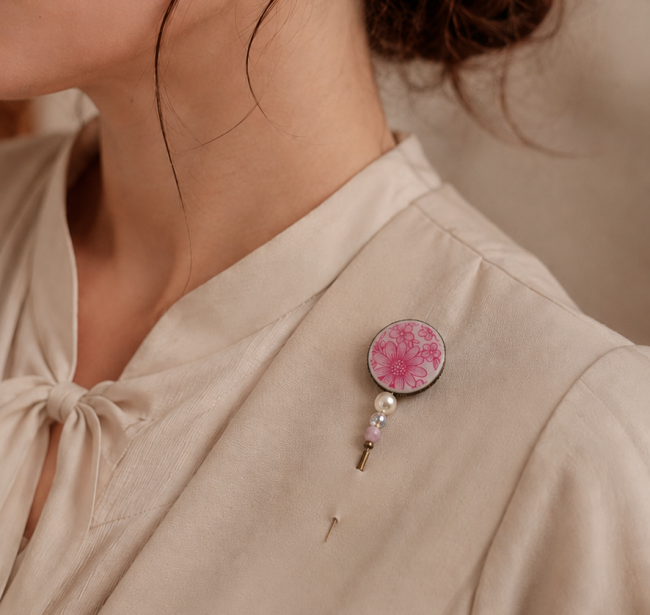 Broche textile en porcelaine ancienne portée sur une veste ou un manteau.