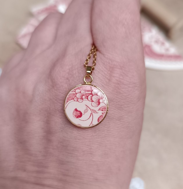 Collier présenté en main pour visualiser le pendentif de 18 mm créé dans le bord d’une ancienne assiette en porcelaine.