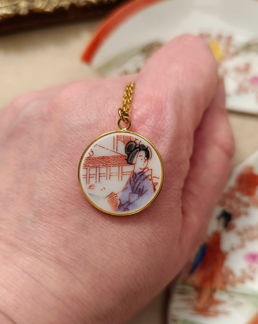 Pendentif Geisha en porcelaine dans la main pour visualiser la taille réelle 22 mm.