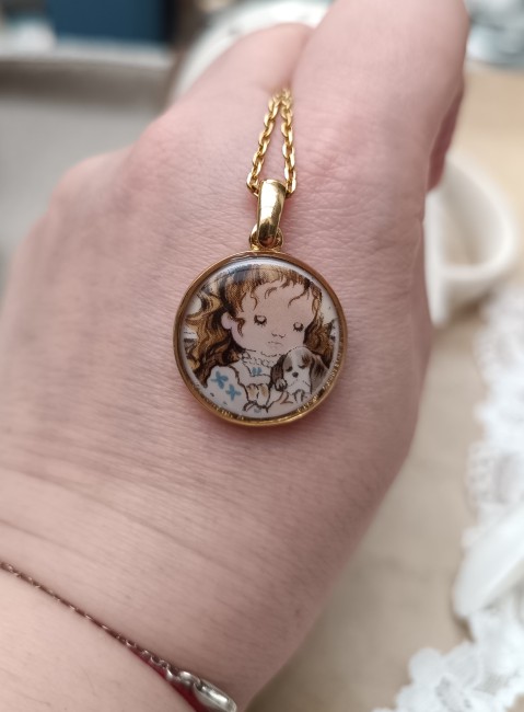 Zoom sur le pendentif en porcelaine ancienne, sculpté et scellé dans la résine pour sublimer le motif Sarah Kay.