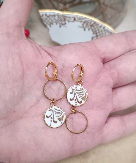 Zoom sur le motif blanc et doré des boucles d’oreilles Orion, sublimé par la résine protectrice pour un bijou unique et durable.