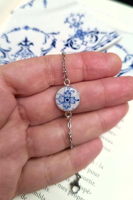 Bracelet artisanal présenté en main avec cabochon de 14 mm créé dans une ancienne assiette en faïence française.