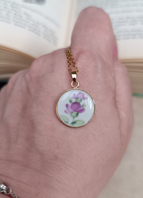 collier-poesie-porcelaine-baviere-18mm-main Collier Poésie présenté en main pour visualiser les proportions de son pendentif floral de 18 mm en porcelaine ancienne.