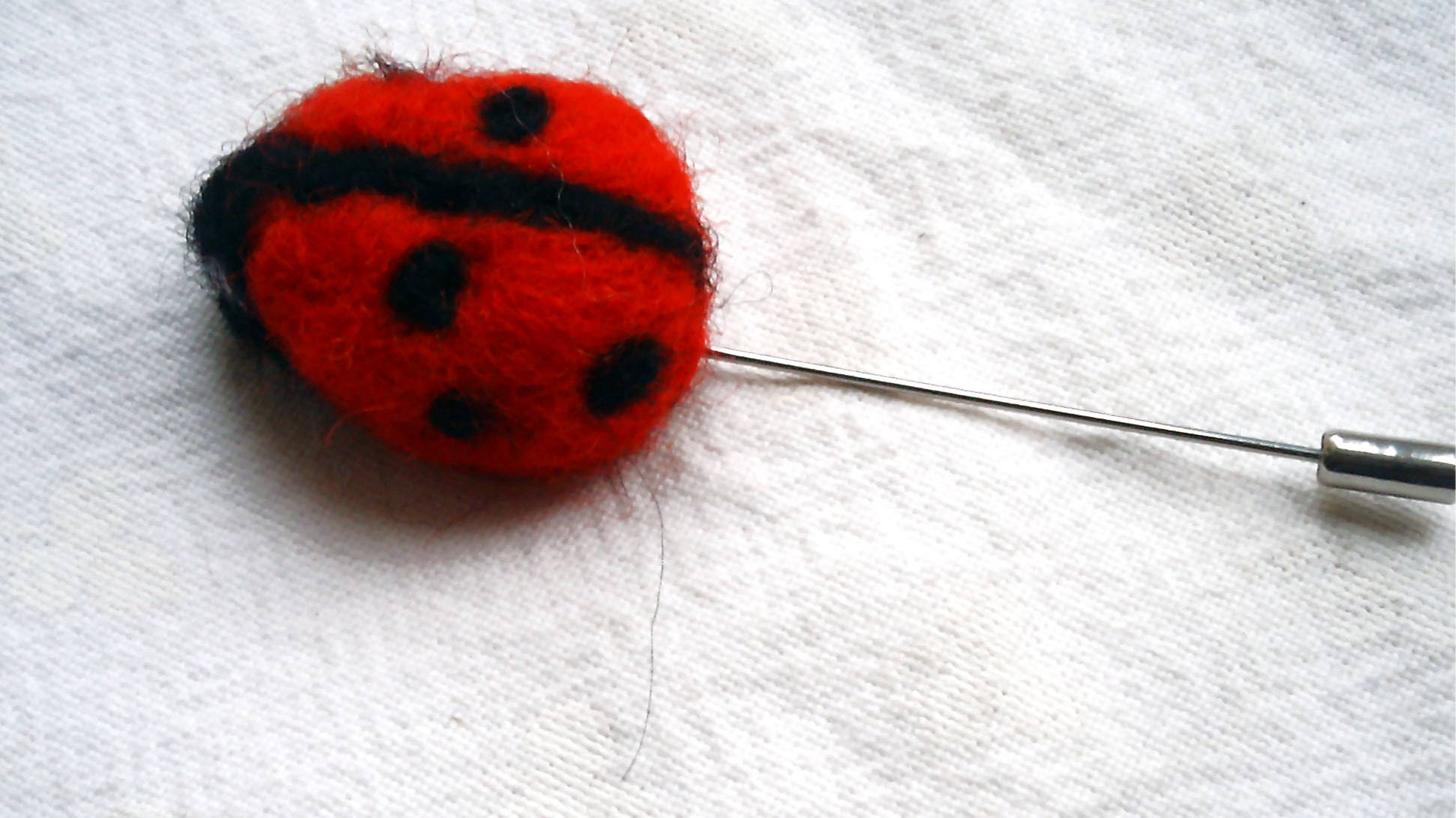 broche coccinelle en laine feutrée à l'aiguille rouge et noire