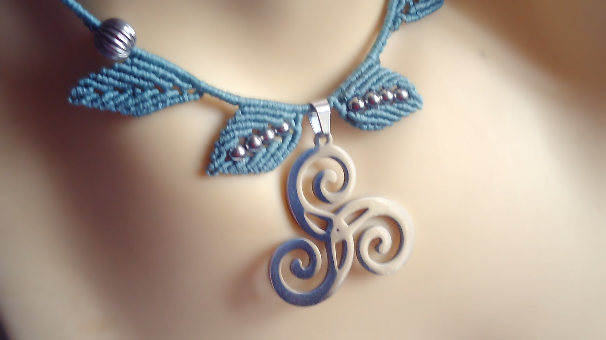 Collier en micromacramé vert et un triskel en acier inoxydable.