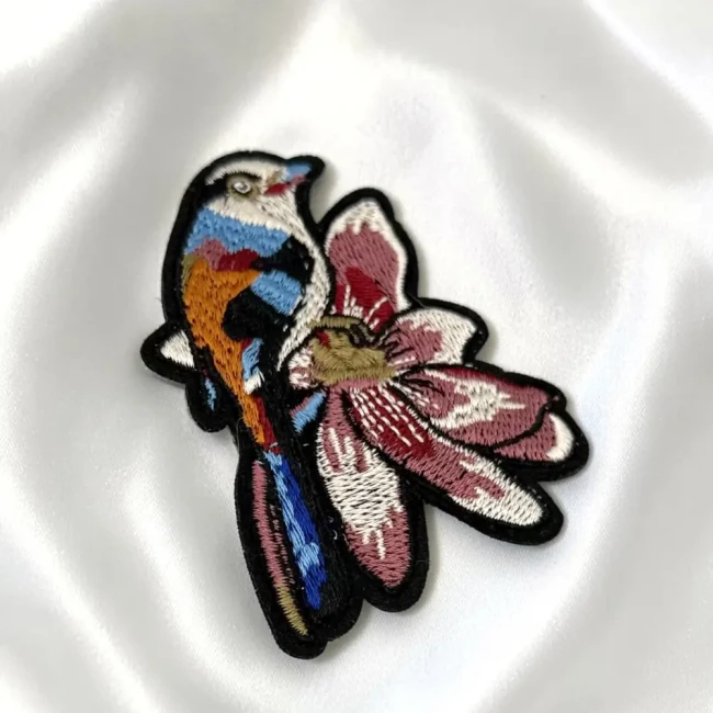 Détails de broderie du patch oiseau et fleur Gros plan sur les détails brodés de l'oiseau et de la fleur