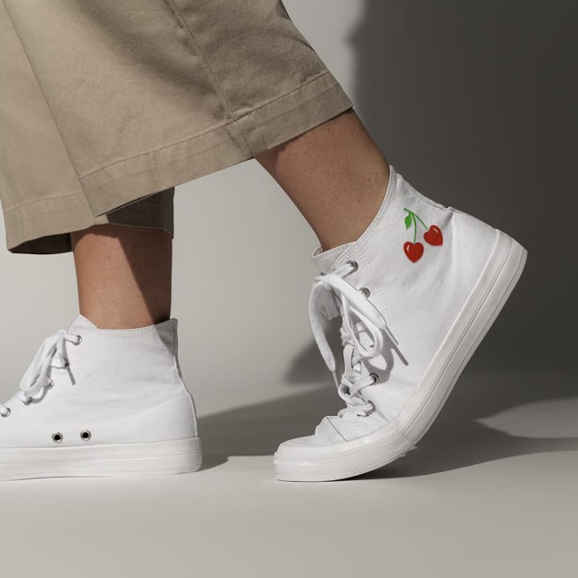 Ecusson thermocollant cerises cœur sur sneakers blanches Patch cerises cœur thermocollé sur des baskets blanches, look fun et décontracté.