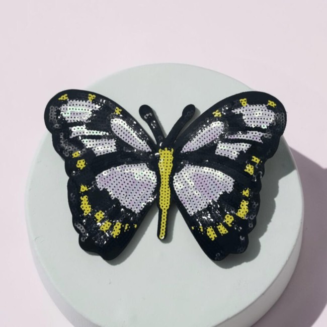 Patch papillon brodé posé sur serviette beige