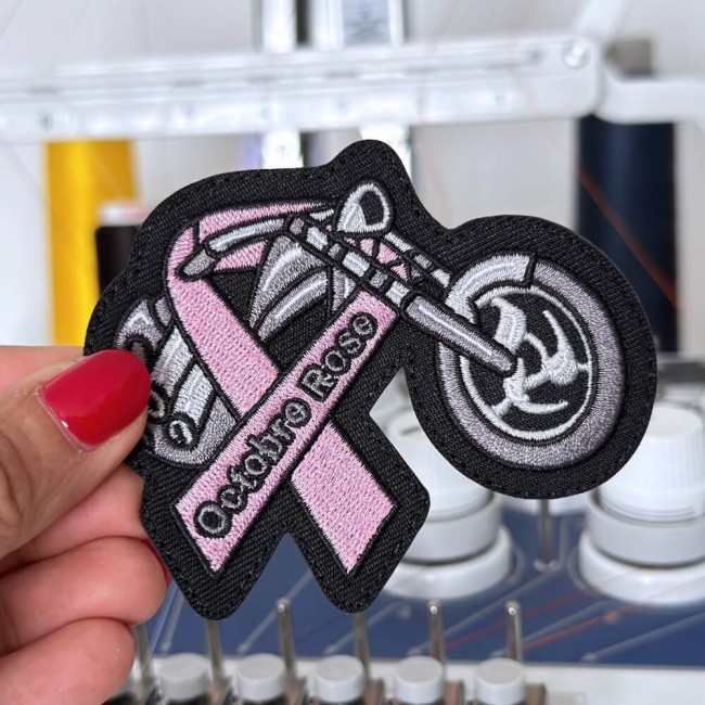 Ecusson ruban rose octobre rose tenu dans ma main devant ma machine à broder Patch ruban rose moto broodé dans mon atelier
