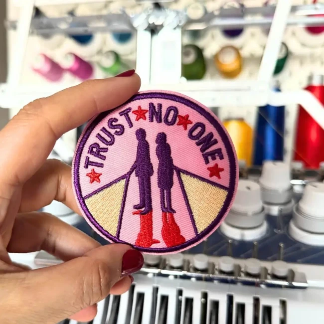 Photo de l'écusson devant ma macine à broder Patch Trust non one dans ma main dans mon atelier