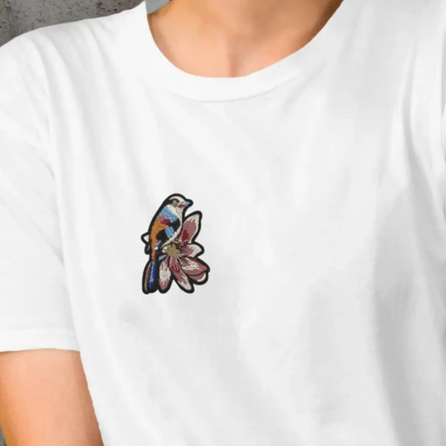 Patch oiseau et fleur posé sur un t-shirt blanc Patch brodé oiseau sur fleur appliqué sur un t-shirt blanc