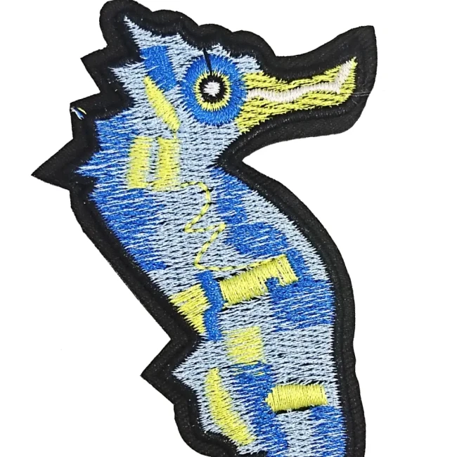 Détail du grand patch hippocampe brodé Détail de la broderie bleue et jaune du patch hippocampe