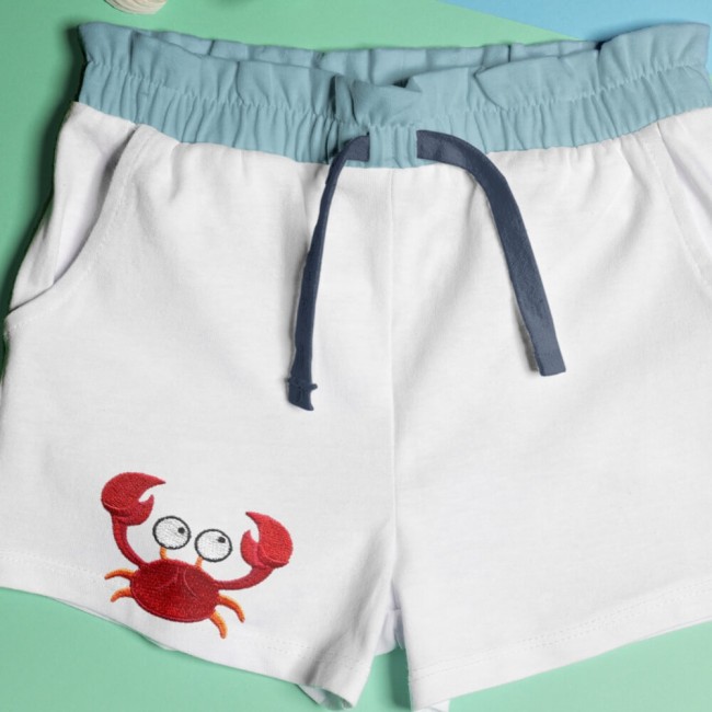 Patch crabe appliqué sur un short blanc d’été avec déco coquillages