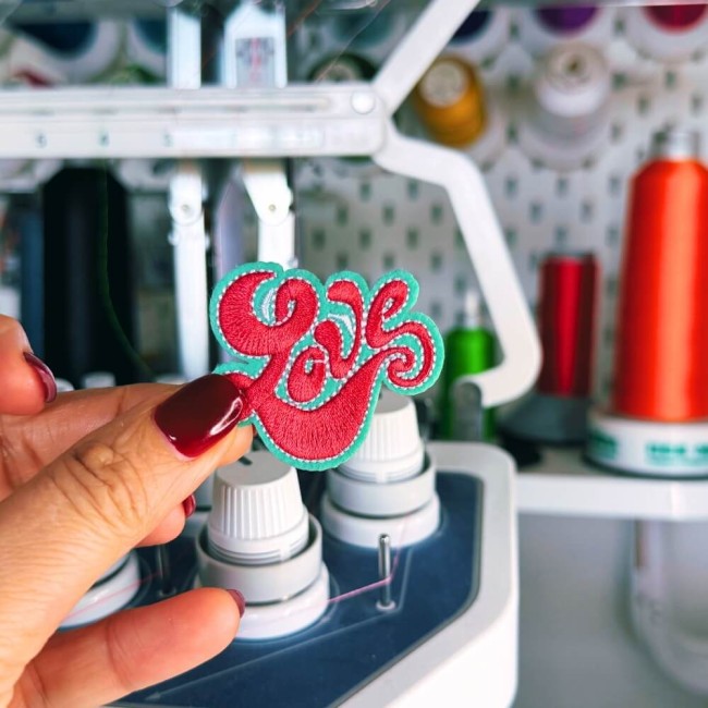 Patch brodé LOVE rétro photographié dans ma main devant ma machine à broder