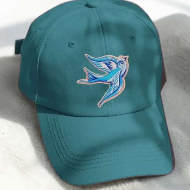 Patch hirondelle bleue rétro posé sur une casquette turquoise