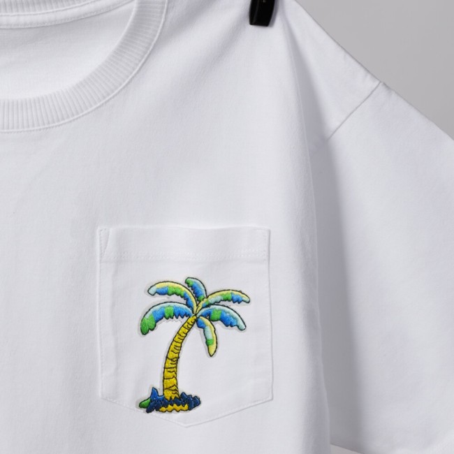 Un patch palmier brodé aux couleurs vives qui customise la poche d'un t-shirt blanc