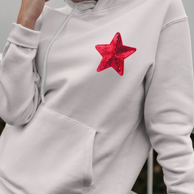 Écusson étoile rouge à sequins sur sweat clair porté par une jeune femme