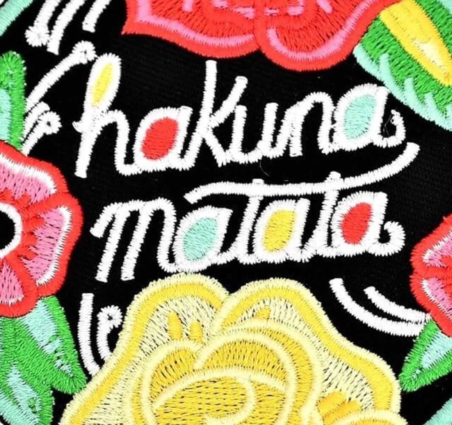 Gros plan sur le lettrage Hakuna Matata brodé et les fleurs colorées