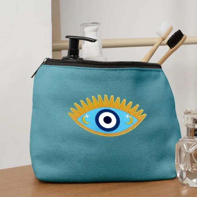 Ecusson mauvais oeil qui customise une trousse Patch thermocollant œil protecteur beige doré et turquoise sur une trousse de maquillage