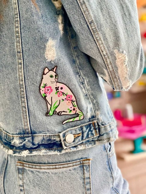 Écusson chat fleuri cousu sur une veste en jean délavé