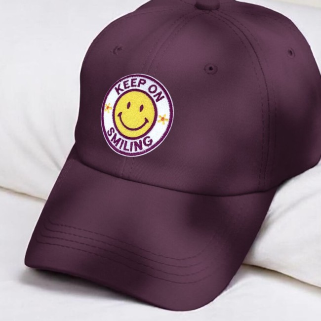 Ecusson thermocollant smiley cousu sur une casquette lie de vin