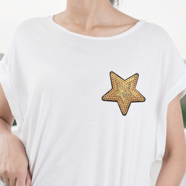 Patch étoile doré à sequins sur un t-shirt blanc porté par une jeune femme