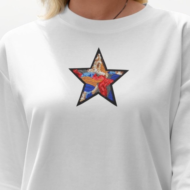 Patch étoile à sequins multicolores sur un sweat blanc porté par une jeune femme