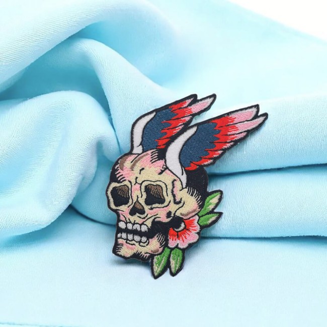 Crâne ailé avec fleur brodé main sur un t-shirt blanc