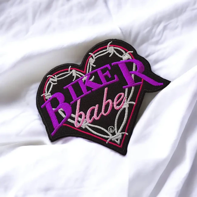 Broderie rose et violette du patch cœur Biker Babe Détail du patch Biker Babe brodé posé sur tissu blanc