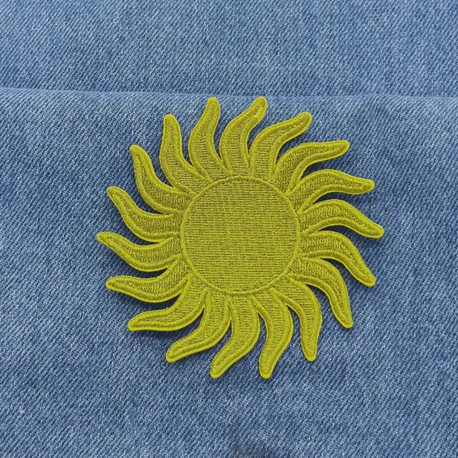 Patch soleil doré thermocollant posé sur un jean