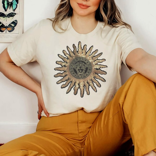 Femme portant un tee-shirt jaune pale avec cette grand applique soleil en sequins dorés