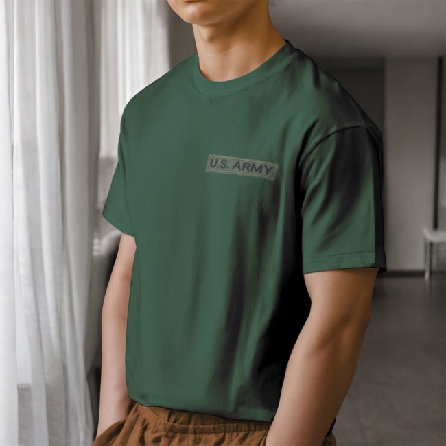 Écusson thermocollant US ARMY noir brodé sur fond kaki, posé sur un vêtement Patch brodé US ARMY kaki et noir posé sur un t-shirt vert