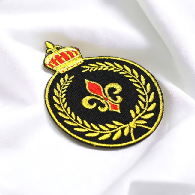 Détail du patch brodé couronne et fleur de lys rouge et or