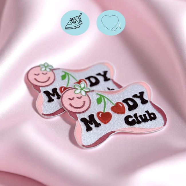 Patchs Moody Club sur fond rose Deux écussons Moody Club brodés sur tissu rose pastel