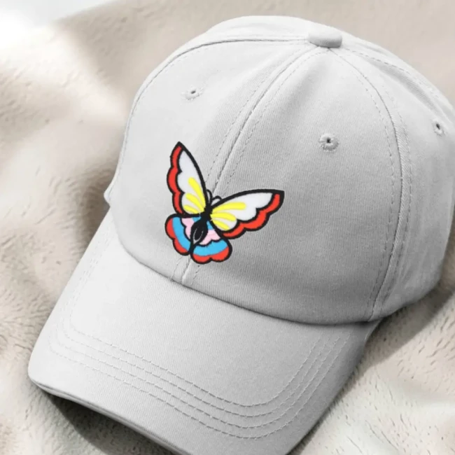 Écusson brodé papillon multicolore sur une casquette Patch papillon multicolore posé sur une casquette gris clair