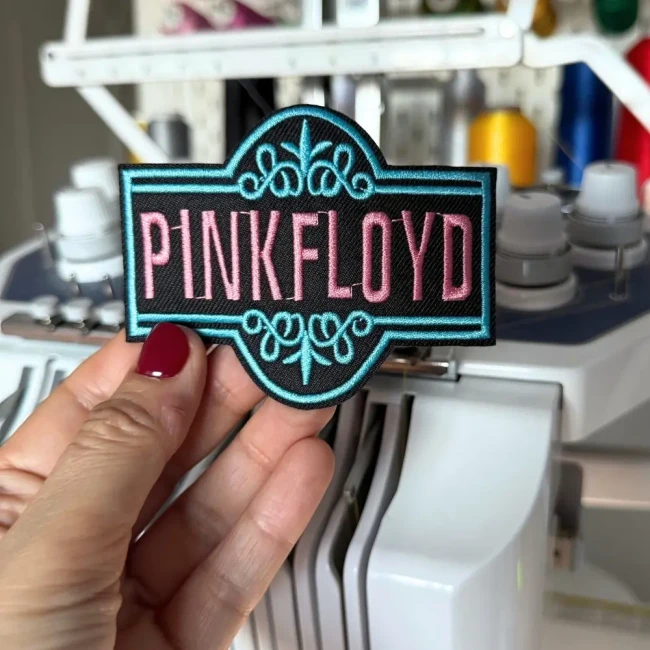 Détail de la broderie du patch Pink Floyd Patch Pink Floyd brodé tenu devant une machine à broder